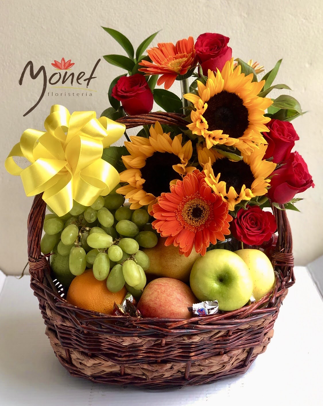 Canasta grande con frutas y flores variadas.