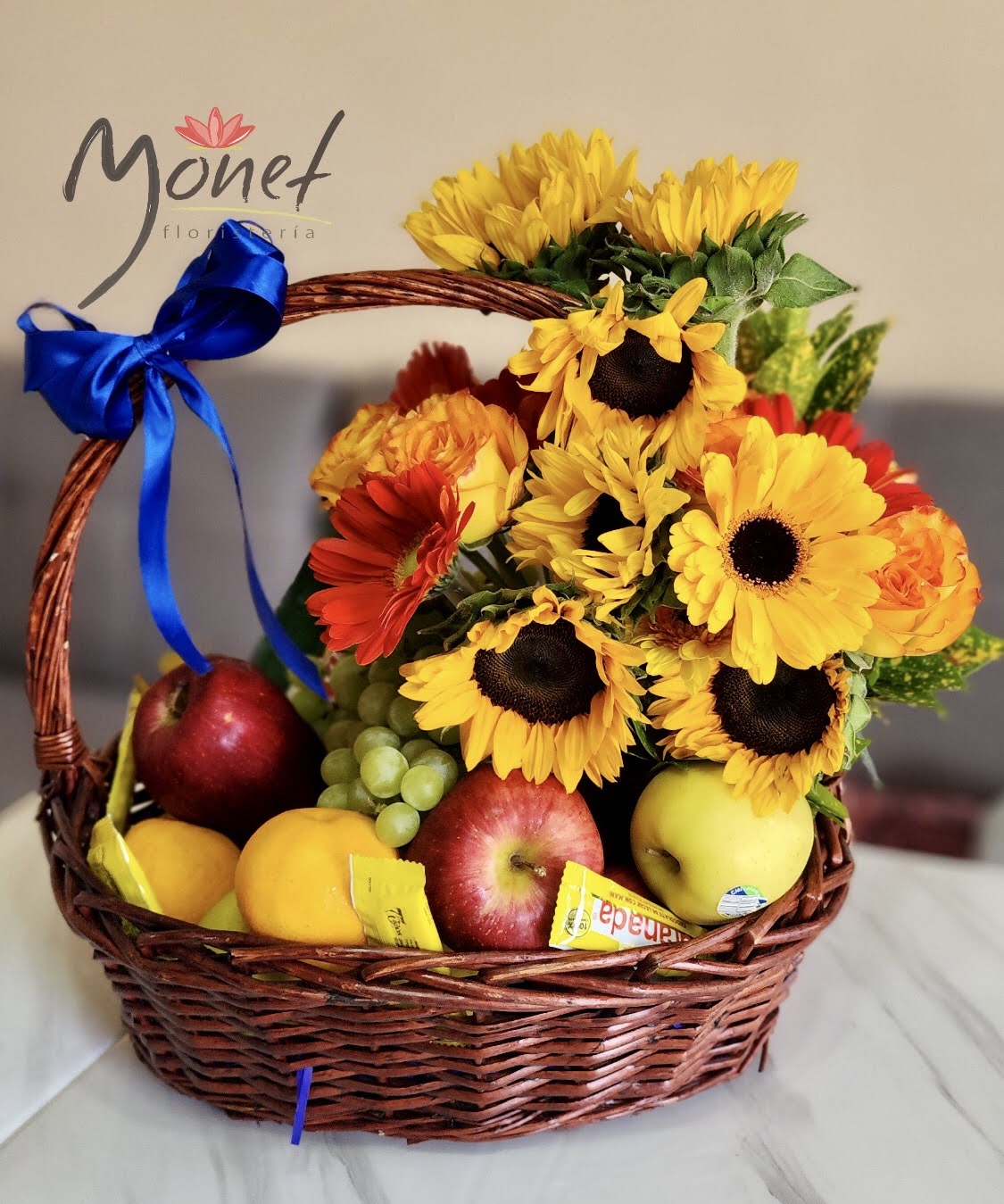 Canasta grande con frutas y flores variadas.
