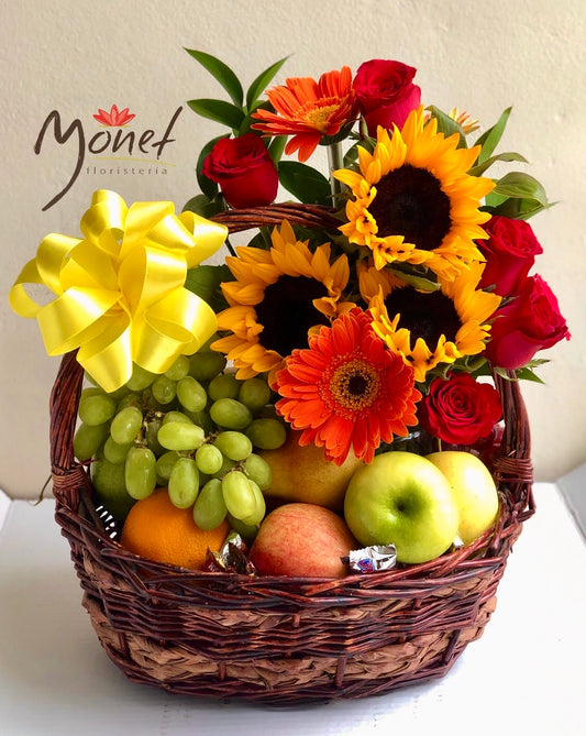 Canasta grande con frutas y flores variadas.